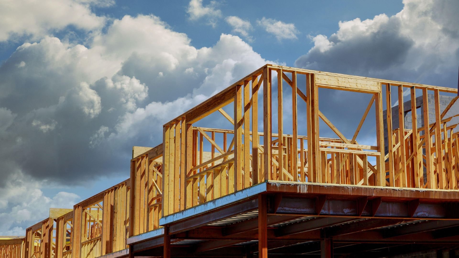 Wooden frame of a house under construction against cloudy blue sky